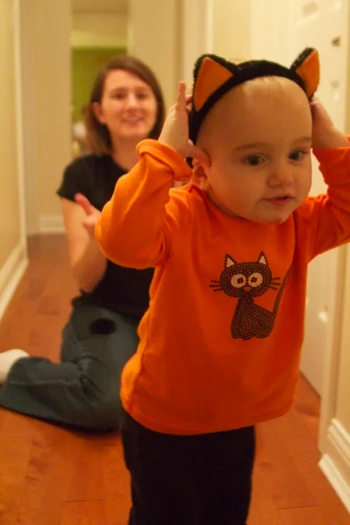 **Our little helper**

It’s been far too long since our last post, and lots has happened since then. In just a few days, our Abigail will be seventeen months old and she’s quite the accomplished talker now. Her vocabulary grows by many words every day. As I type this, she’s happily shouting “dog” while watching a Barney episode about a dog show. She loves this episode. She also just told me to “look” at her while she hung a toy from her arm, and then grabbed a book and told me to “read.”. She’s not yet speaking in full sentences, but she did ask John for more crackers the other day by saying “Pappa. Cracker. More.” That’s pretty close to a full sentence!  
  
I got excited about posting something here yesterday when she got up in the morning, pulled her laundry basket out of her closet, and declared “launny.” She knows that we usually wash the laundry on Thursdays, and she was ready to get started. She’s quite the helper. She also really likes to help us empty the dishwasher. I’m still amazed by how much she likes to “help.”  
  
The other night, we were trying to encourage better sleeping habits. Our girl surprised us. She fussed for Momma, but I didn’t get up. She then called for Papa. When Papa didn’t respond, she called for “Dino.” When Dino didn’t respond, she decided to go back to sleep.  
  
Here’s a cute picture from Halloween. She loves kitties.