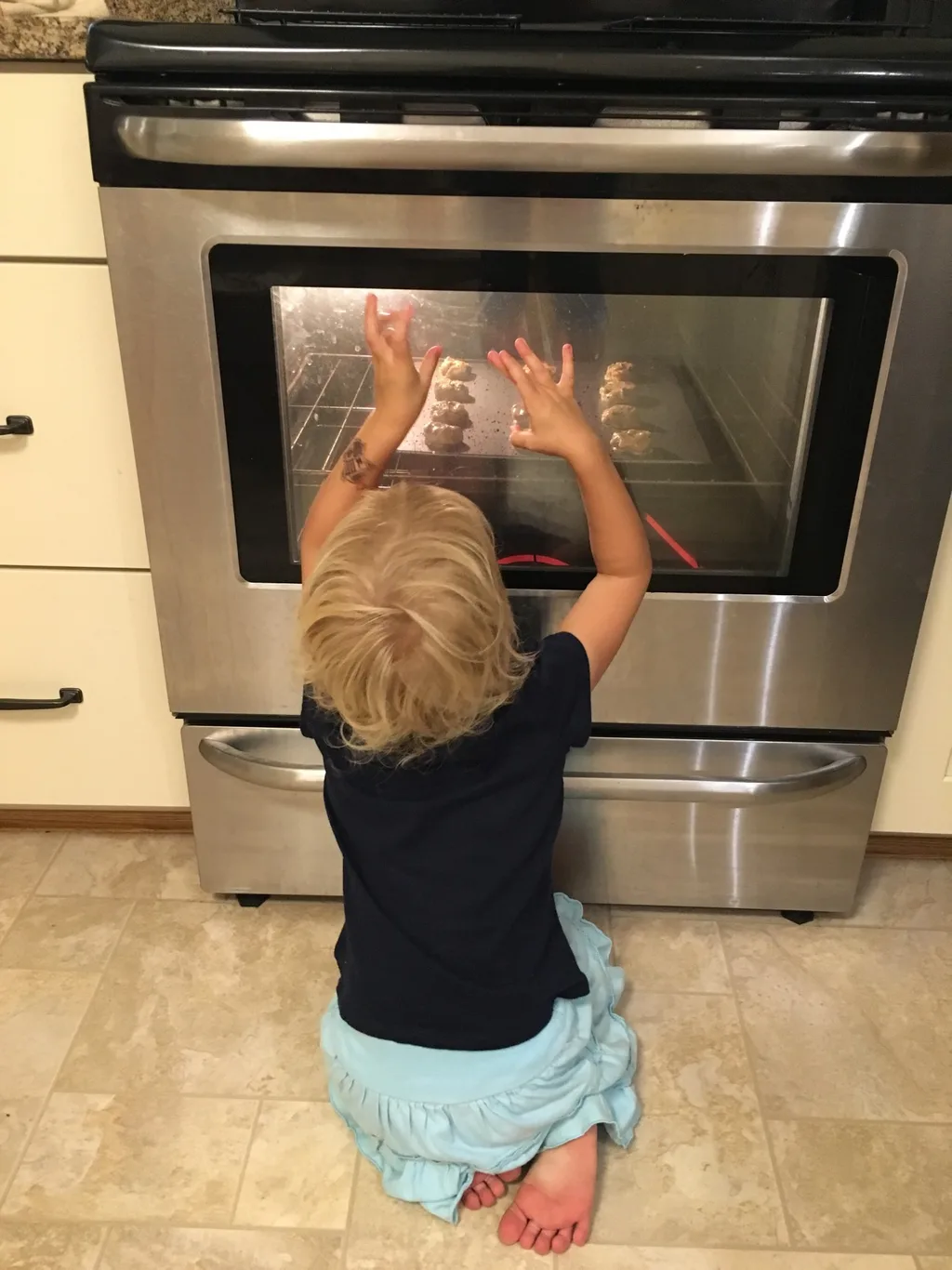 After helping measure, mix, and shape, Gwen keep a close watch on her cookies.